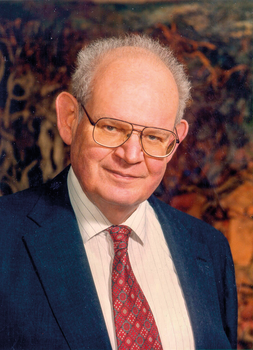 Elegáns férfi öltönyben és nyakkendővel Elegánsan öltözött férfi sötétkék öltönyben, fehér csíkos ingben és piros mintás nyakkendővel.